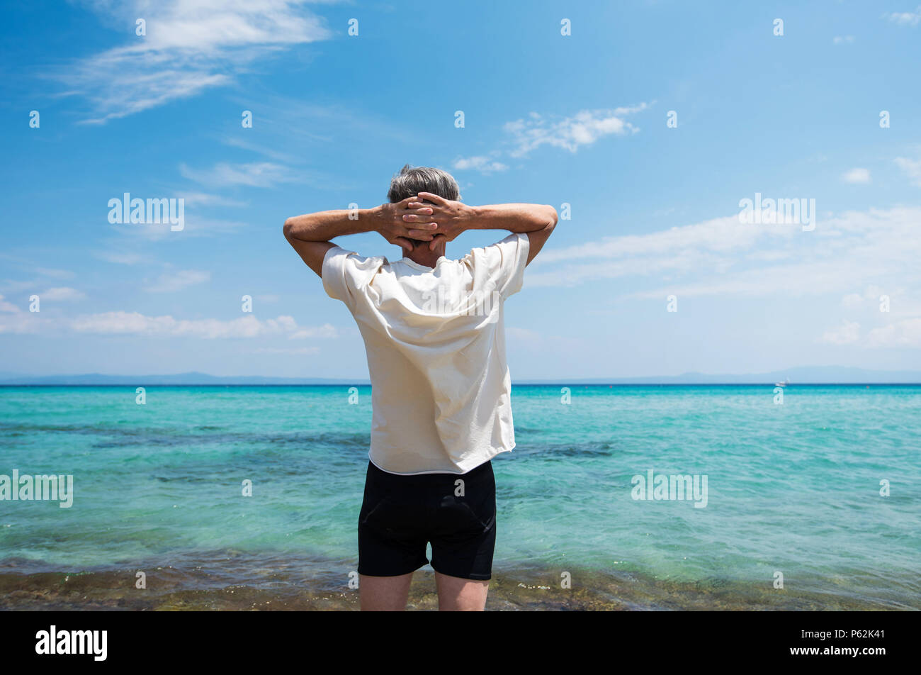 Hombre Senior disfrutando de vistas al mar en las vacaciones de verano Foto de stock