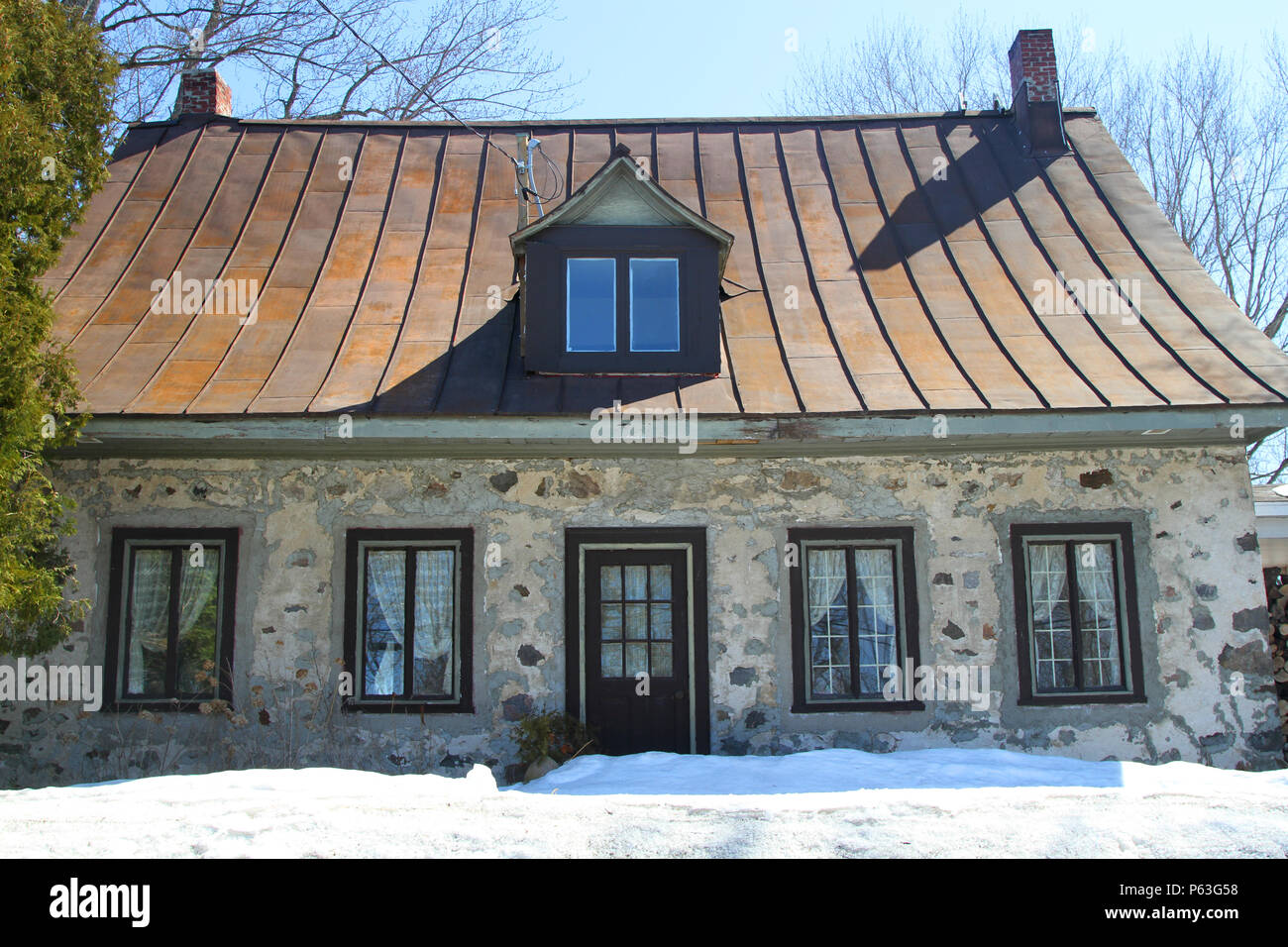 Vintage francés canadiense casa victoriana de piedra con buhardilla encima de la puerta y tejado rojo Foto de stock