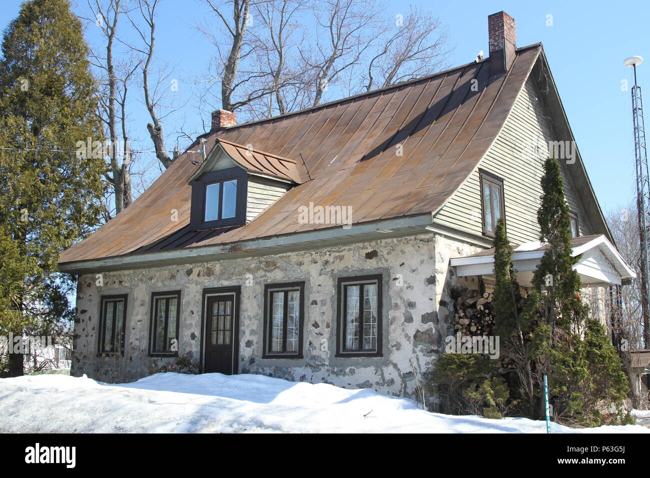 Vintage francés canadiense casa victoriana de piedra con buhardilla encima de la puerta y tejado rojo Foto de stock