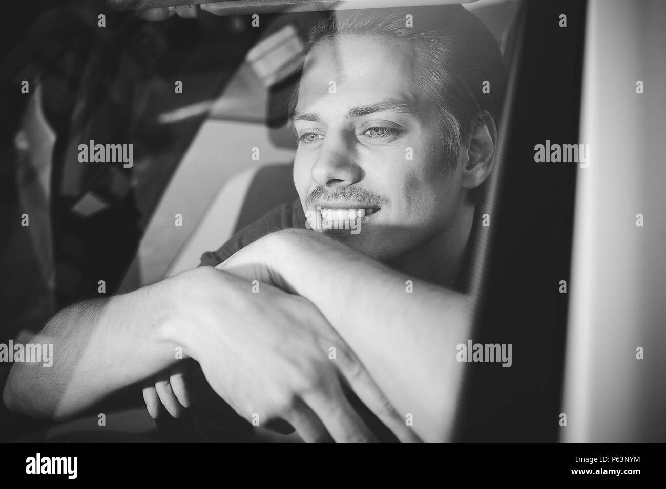 Disfrute de la unidad. Imagen del guapo joven sentado en el coche. Foto de stock