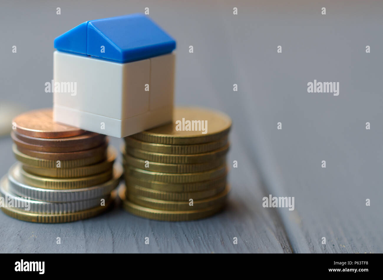 El concepto de préstamos para la vivienda. Casa Blanca con un techo azul sobre un montón de monedas Foto de stock