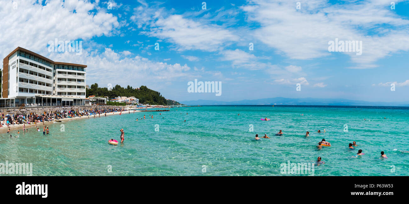 Chaniotis, Grecia - Junio 23, 2018: Chaniotis city beach y el mar claro de Chalkidiki con muchos turistas, Grecia destino costero Foto de stock