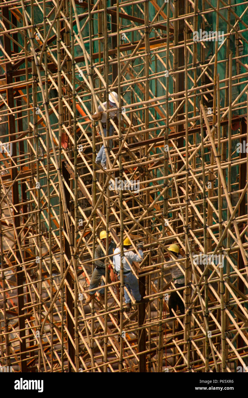 Los trabajadores de la construcción en un típico edificio de bambú chino andamio en un gran sitio en construcción en el centro de Macao. Foto de stock