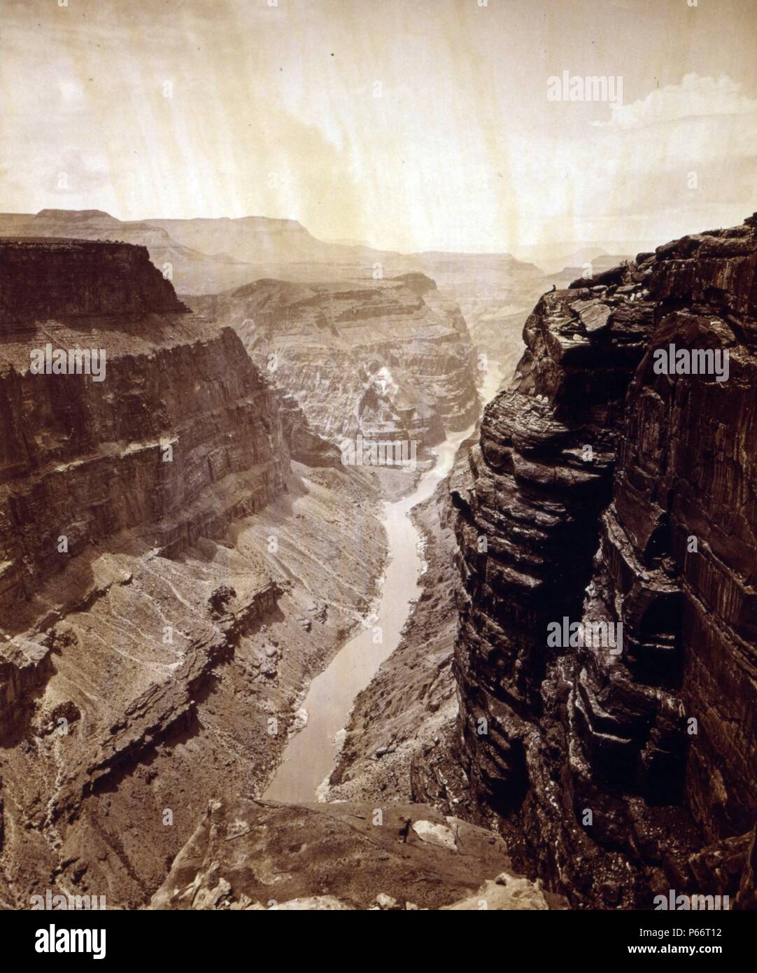 Gran Cañón del Río Colorado, mirando al oeste por James Fennemore, 1849-1941, fotógrafo 1872. Vista desde la parte superior del Grand Canyon. Hombre sentado en anaquel es John Hillers. Foto de stock