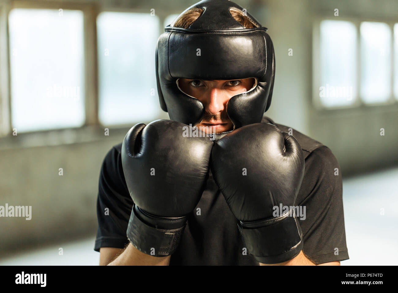 Boxer retrato vestido de negro camiseta, una máscara y guantes de boxeo en  manos vacías ubicación industrial Fotografía de stock - Alamy