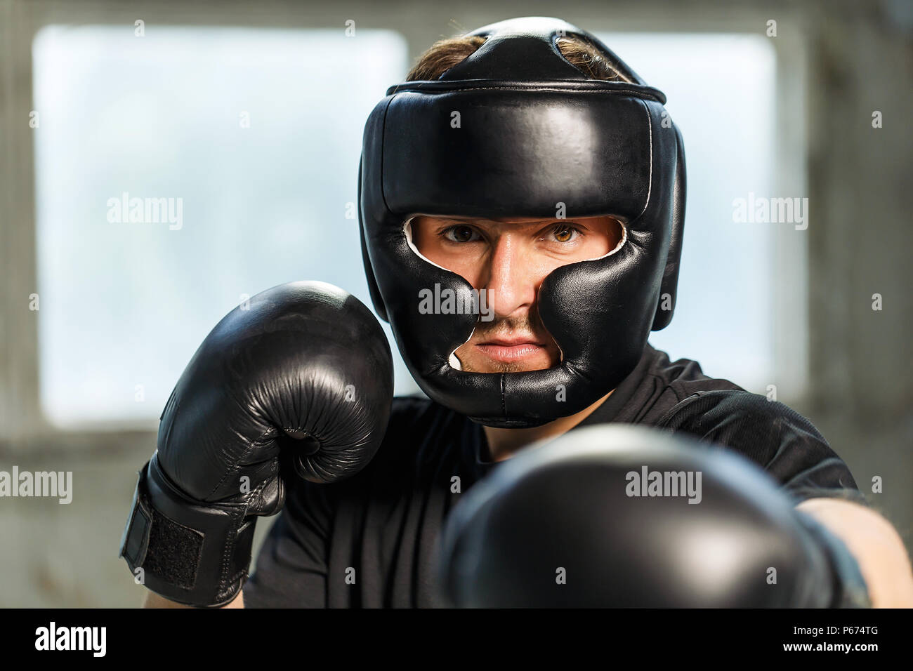 Boxer retrato vestido de negro camiseta, una máscara y guantes de boxeo en  manos vacías, lucha posición ubicación industrial Fotografía de stock -  Alamy