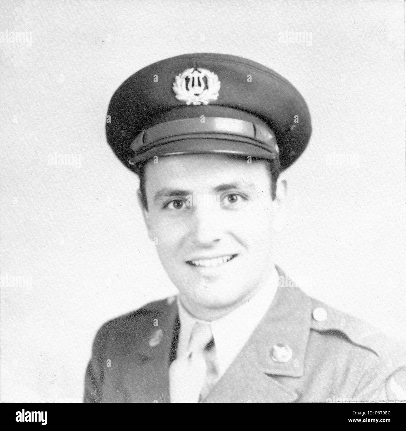 Fotografía en blanco y negro, mostrando un headshot formal de un macho soldado, mirando hacia la cámara, con un tímido sonrisa en su rostro, vistiendo un uniforme de la Fuerza Aérea con un pin en la solapa y tapa con una insignia de la banda del ejército de los Estados Unidos, probablemente fotografiado en Ohio durante la II Guerra Mundial, en 1945. () Foto de stock