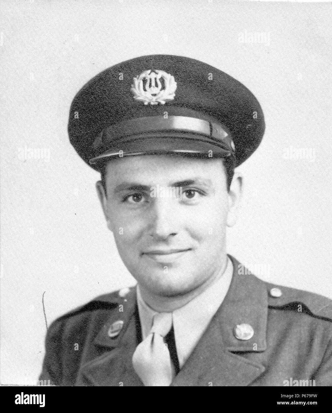 Fotografía en blanco y negro, mostrando un headshot formal de un macho soldado, mirando hacia la cámara, con una muy ligera sonrisa, vistiendo un uniforme de la Fuerza Aérea con un pin en la solapa y tapa con una insignia de la banda del ejército de los Estados Unidos, probablemente fotografiado en Ohio durante la II Guerra Mundial, en 1945. () Foto de stock
