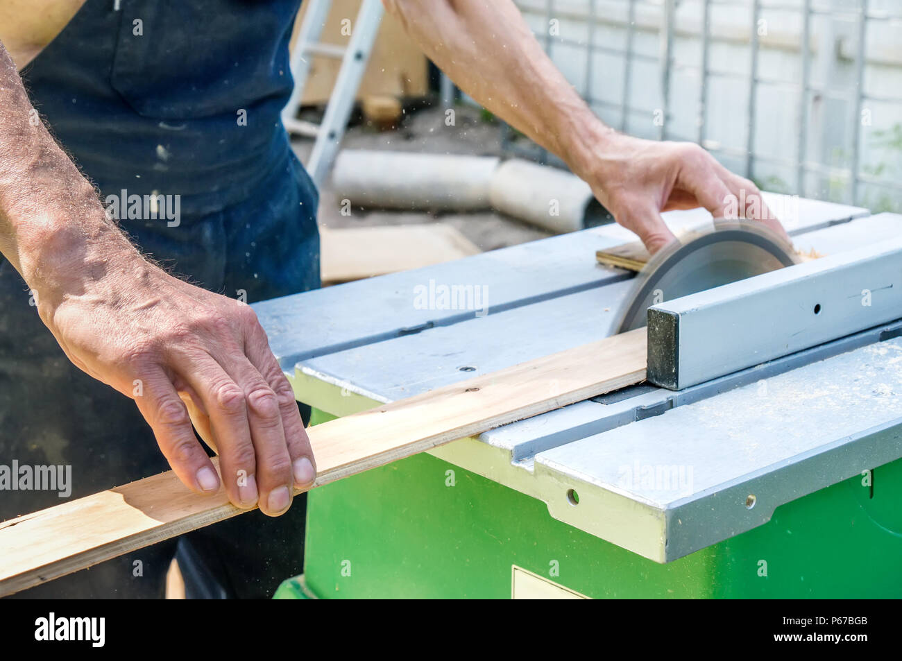 El maestro agudiza el panel de madera con una lijadora eléctrica en un día  soleado en el jardín. Cerca Fotografía de stock - Alamy