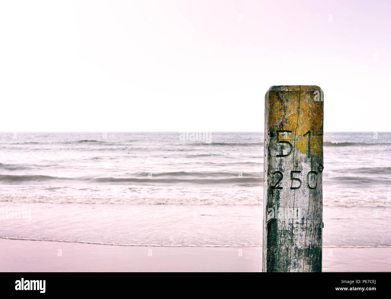 Poste de madera en la playa con una suave luz y espacio de copia. Foto de stock