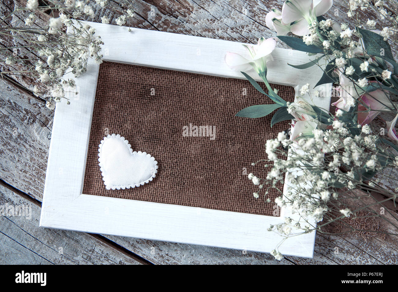 Marco de fotos en blanco y flores blancas sobre fondo de tabla de madera Foto de stock