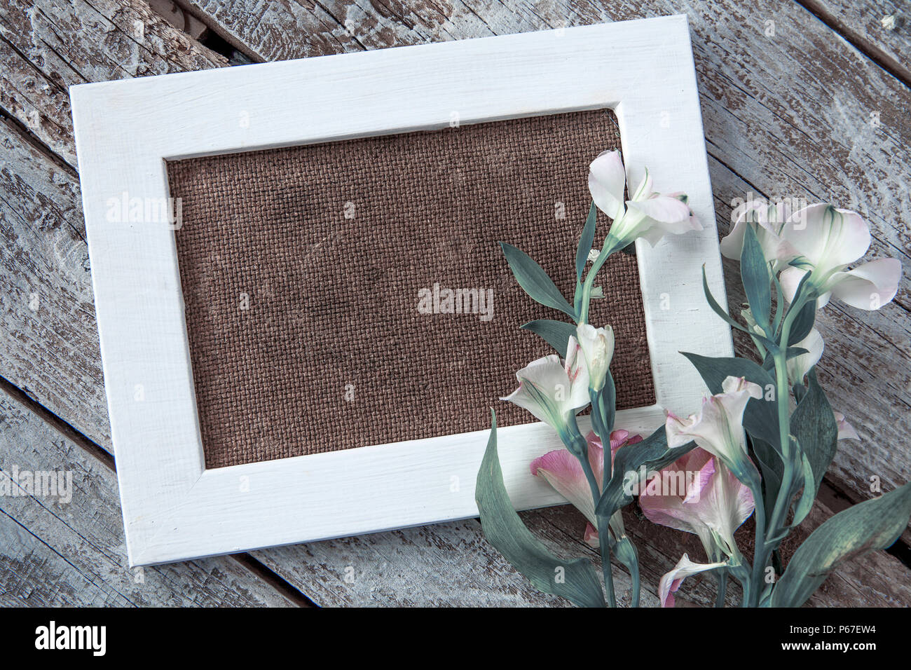 Marco de fotos en blanco y flores blancas sobre fondo de tabla de madera Foto de stock