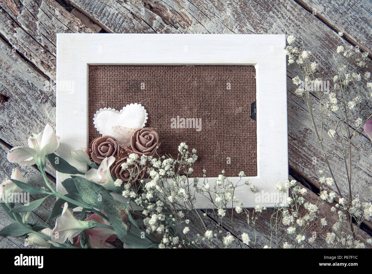 Marco de fotos en blanco y flores blancas sobre fondo de tabla de madera Foto de stock