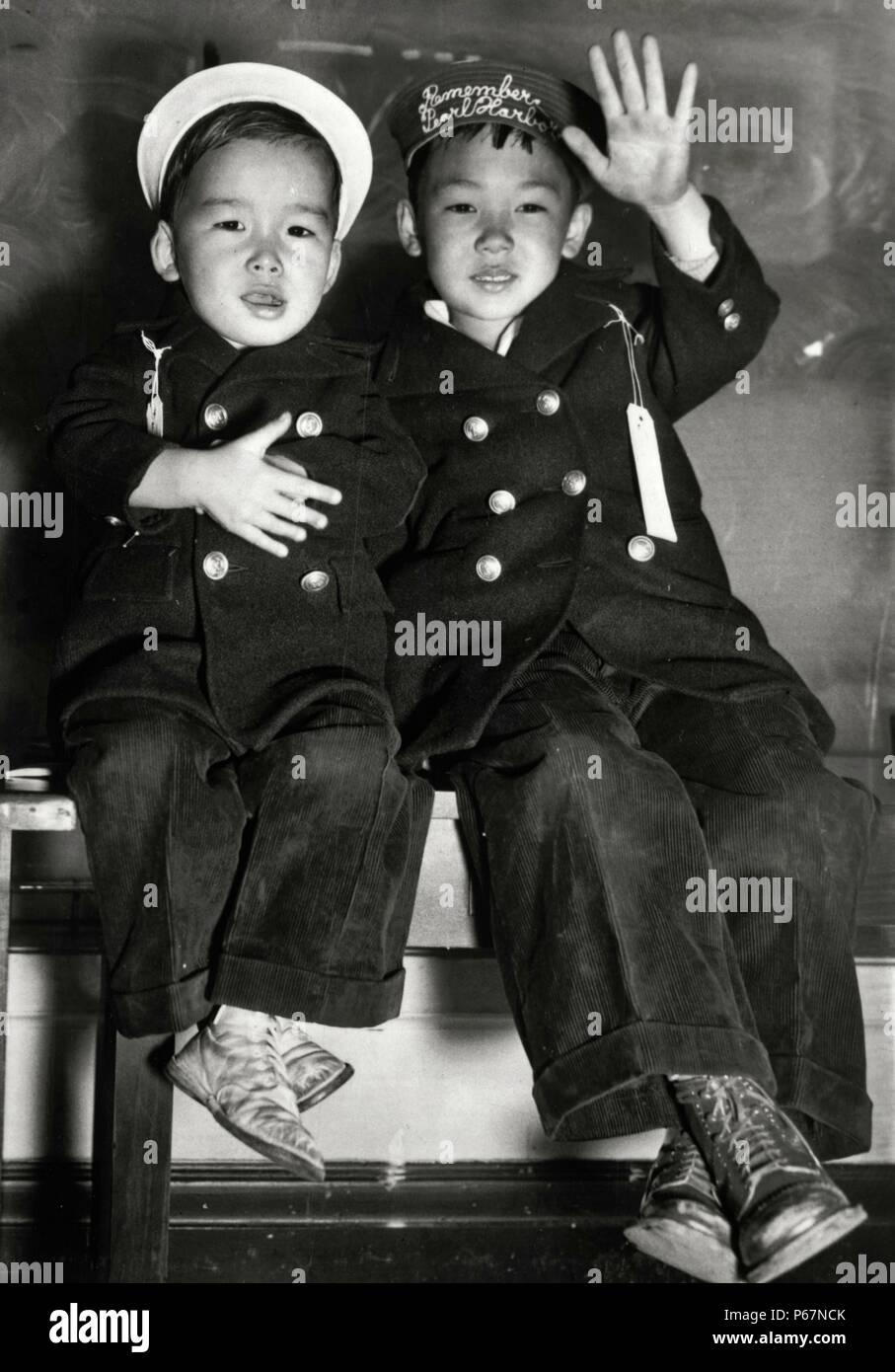 La imagen muestra dos niños japoneses esperando el autobús. Uno de los hat del niño lee "Remember Pearl Harbor". El sombrero del otro niño lee 'Wave Good-bye". Tomada en San Francisco, fechada alrededor de 1942. Foto de stock