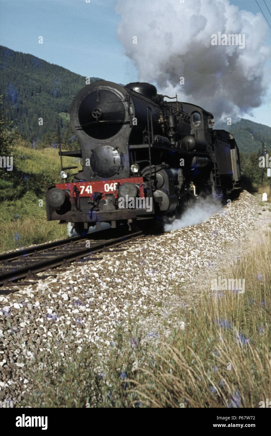 Las montañas Dolomitas hacer un ajuste fino para este italiano Crosti boilered 741 Clase 2-8-0 a la cabeza de un tren de pasajeros entre la Fortezza y San Foto de stock