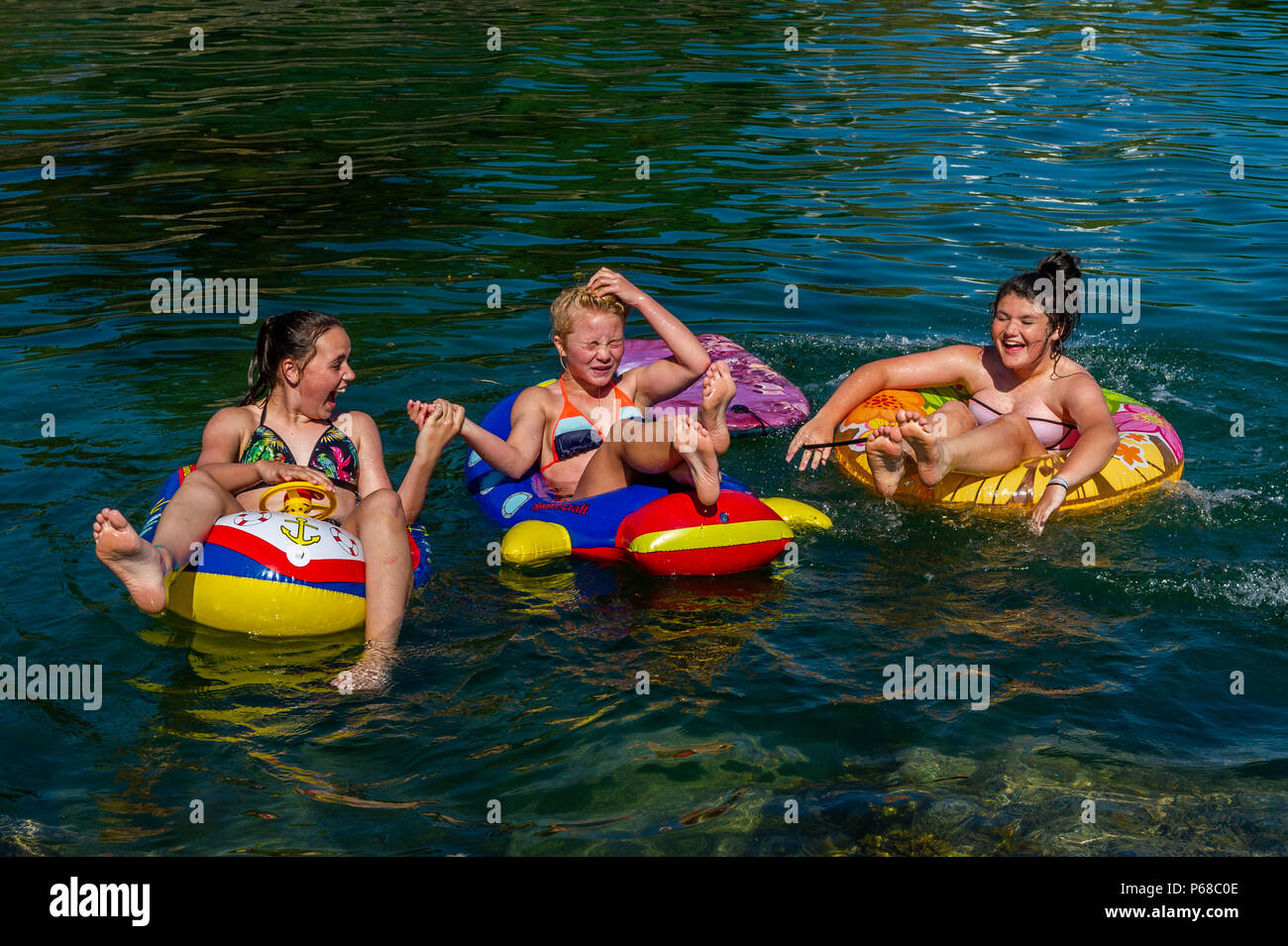 Schull, Cork Occidental, Irlanda. 28 de junio de 2018. Tres niñas hacen el máximo partido del sol jugando en el agua en Schull. Las temperaturas se mantendrán en los 20ºC más altos mañana, pero se prevé que llueva durante el fin de semana. Crédito: Noticias de AG/Noticias en vivo de Alamy. Foto de stock