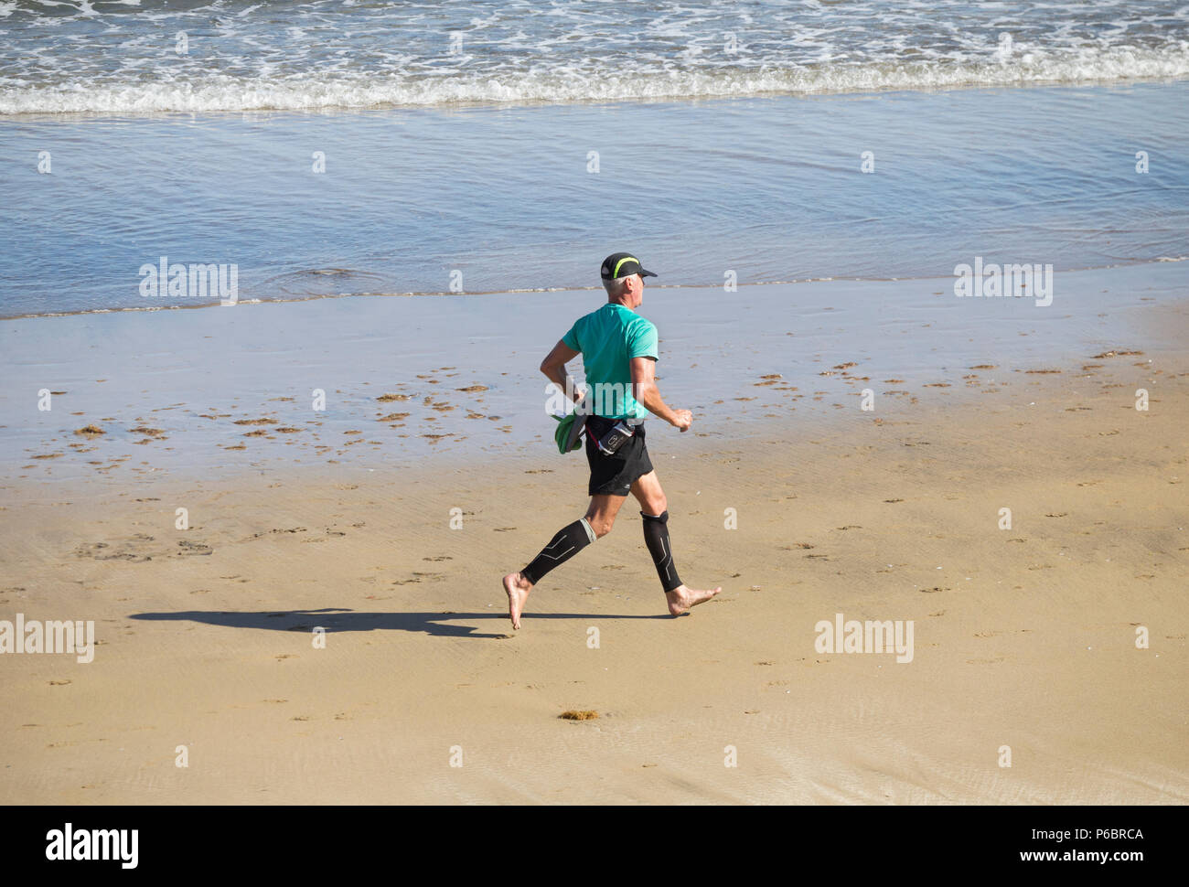Hombre maduro vistiendo calcetines/medias compresión girando la playa Fotografía stock -