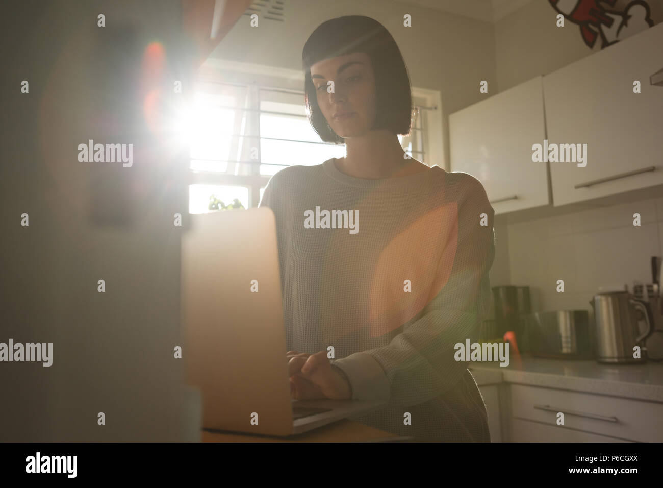 Mujer usando el portátil en la cocina de casa Foto de stock