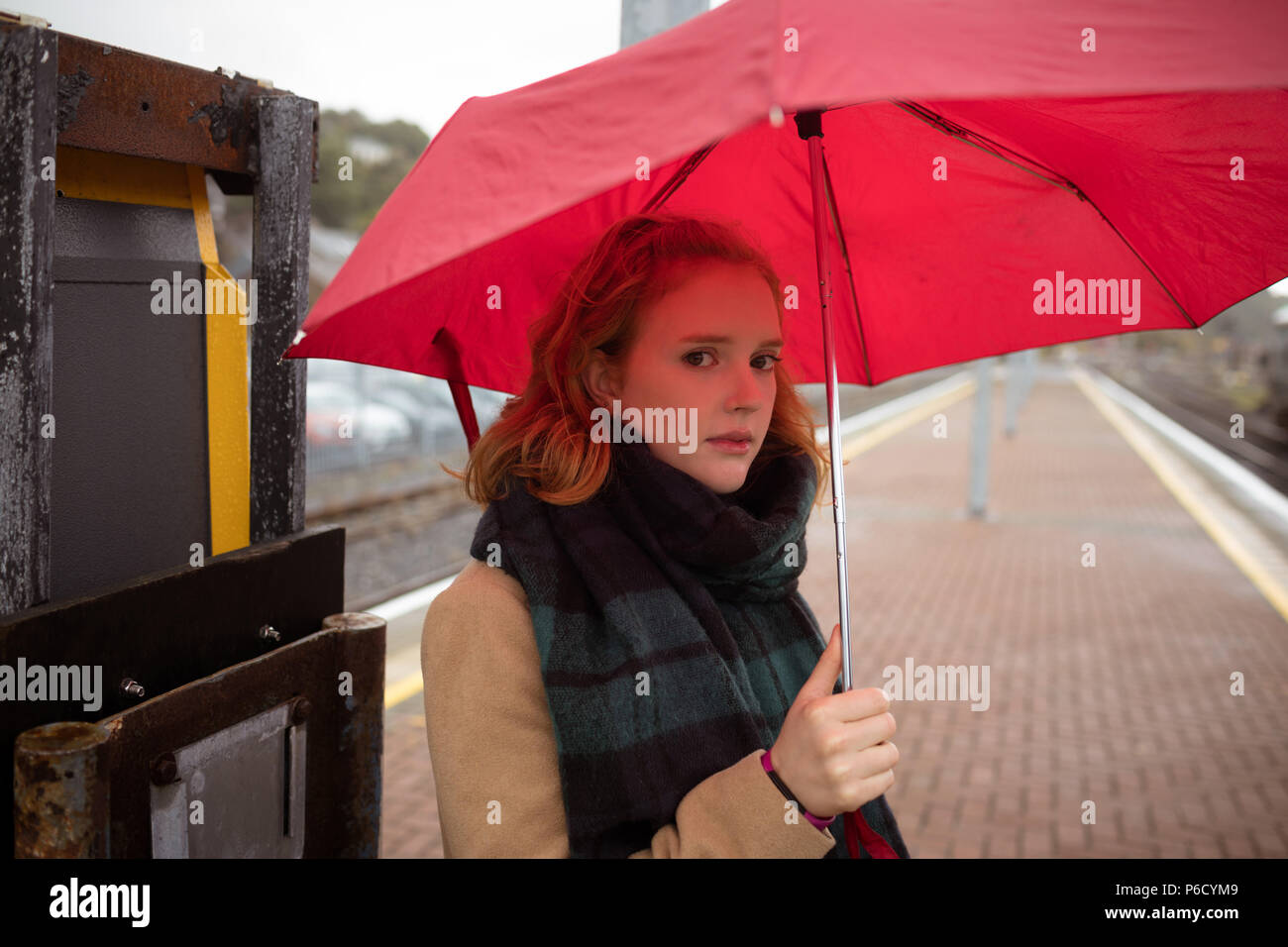 Mujer joven con sombrilla esperando el tren en la plataforma Foto de stock