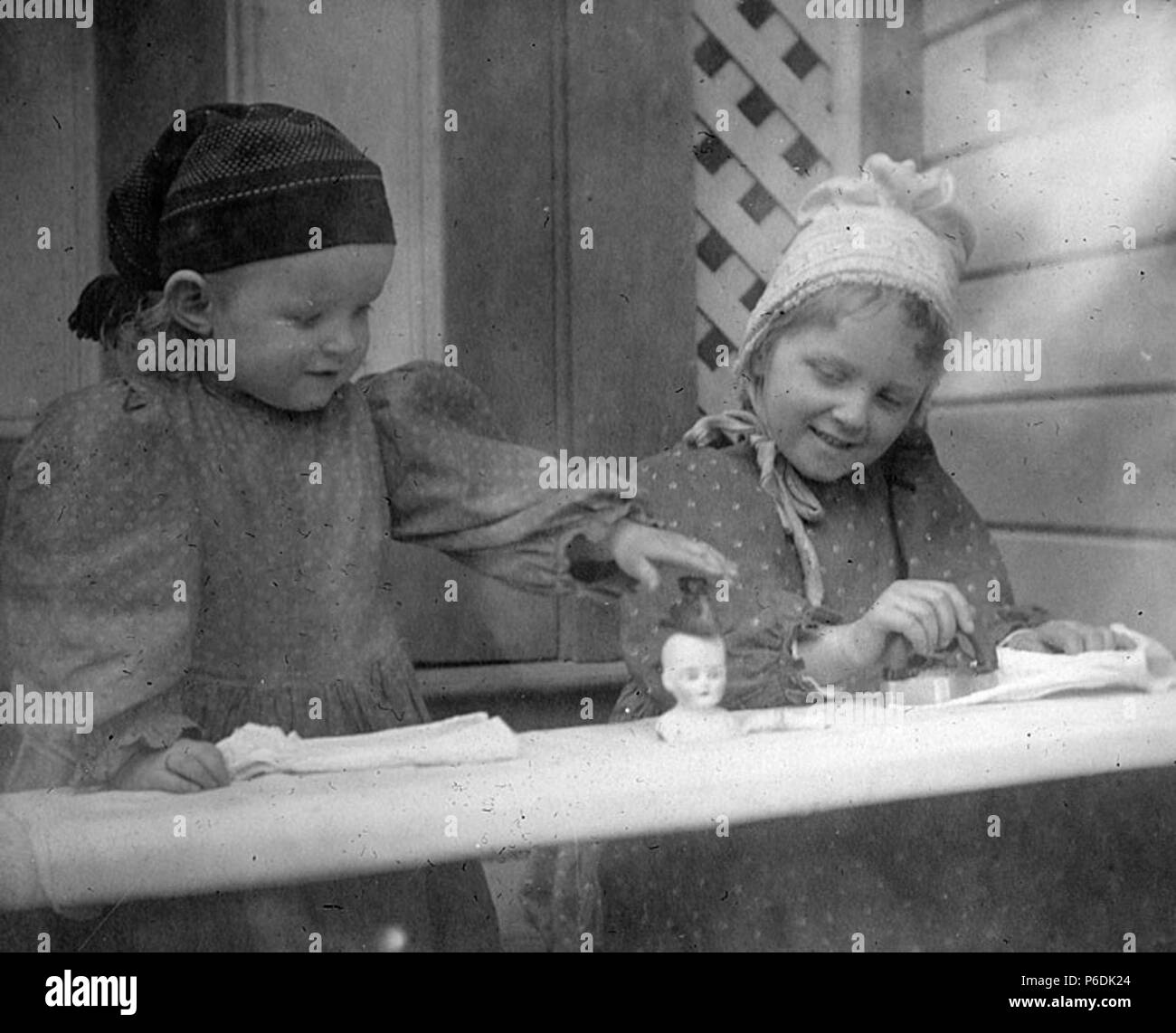 Inglés: Laura y Miriam Kiehl jugando con muñecas y tabla de planchar en la  residencia de su familia, 105 Republicano St., Seattle, Washington, en  enero de 1897 . Inglés: Texto de