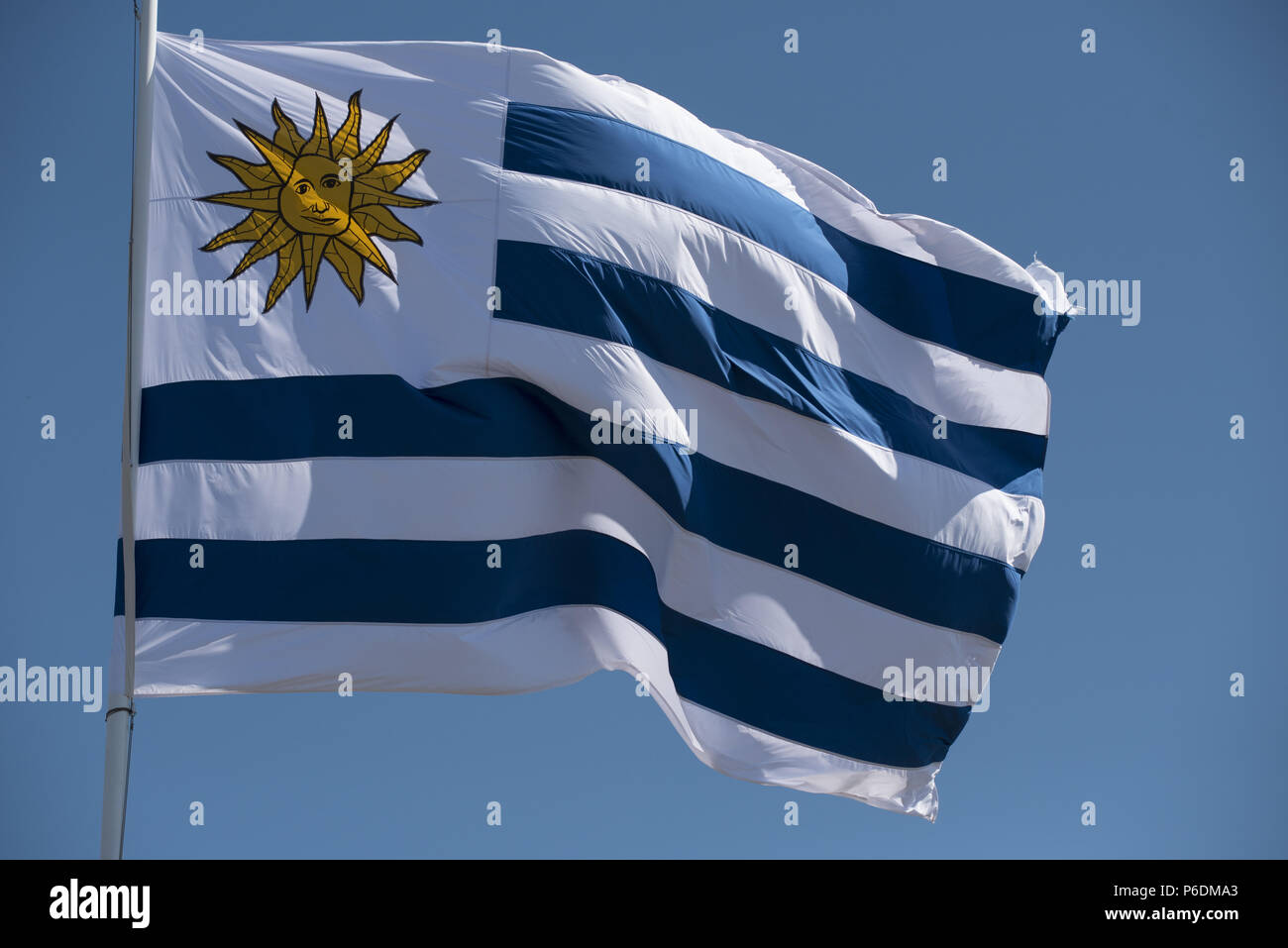 Uruguay bandera del país ondeando al viento sobre fondo de cielo azul. Emblema nacional uruguayo de América del Sur. Foto de stock