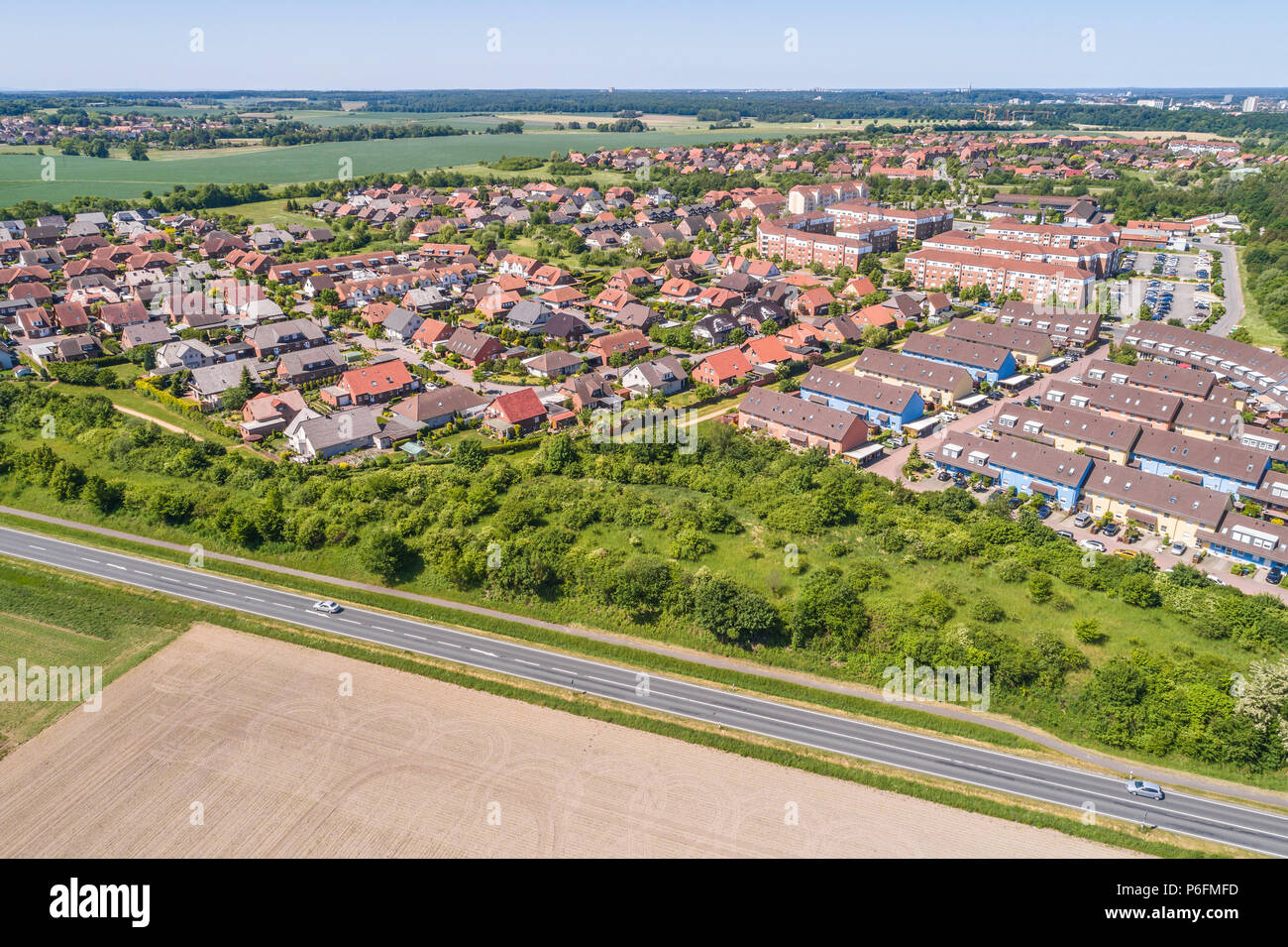 Vista aérea de un barrio de las afueras de Wolfsburg en Alemania, con casas unifamiliares, casas adosadas y unifamiliares, tierras cultivables en el f Foto de stock