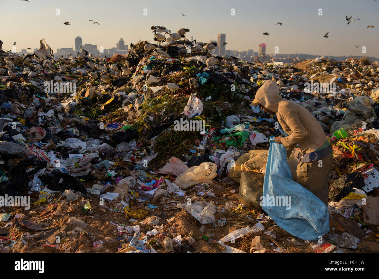 Un recolector de basura ordena a través de los vertederos profundos Robinson en Sudáfrica la capital comercial del país, de Johannesburgo. Foto de stock