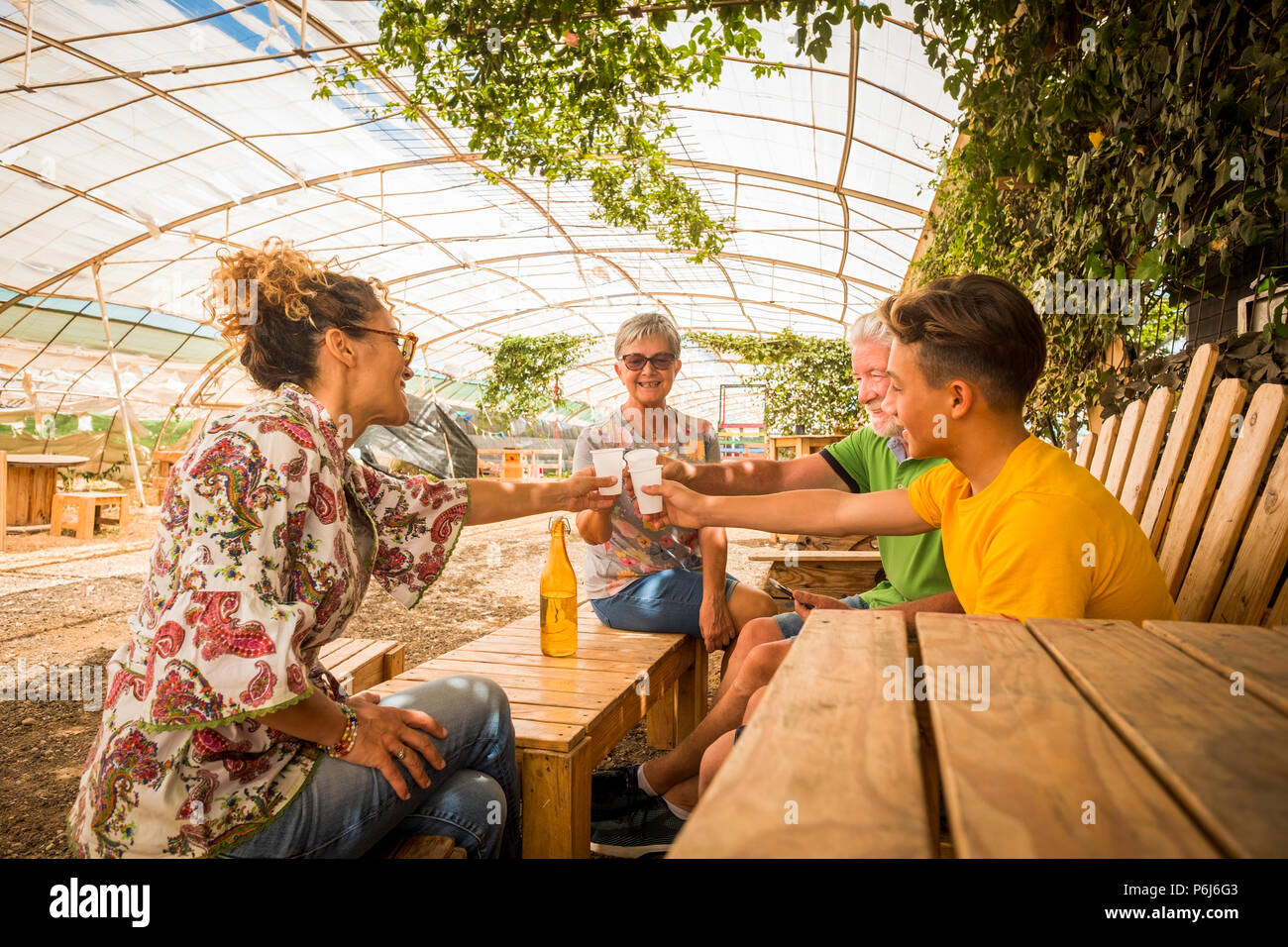 Familia cheers y beber juntos en actividad de ocio al aire libre en el restaurante hechas por madera reciclada y en relación con la naturaleza. Todos sonrientes Foto de stock