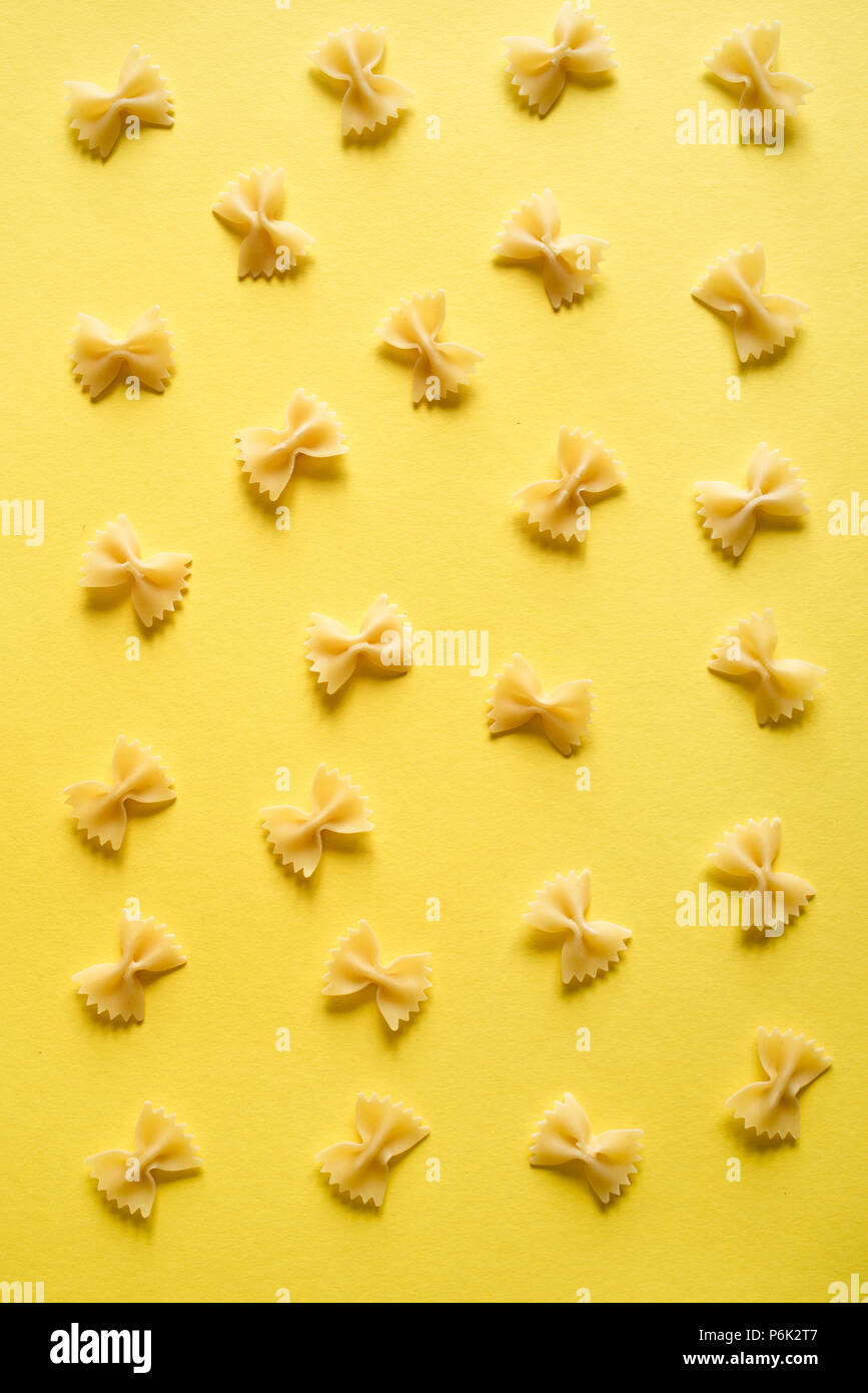 Pasta Farfalle sobre fondo amarillo, vista superior, plano laical. Foto de stock
