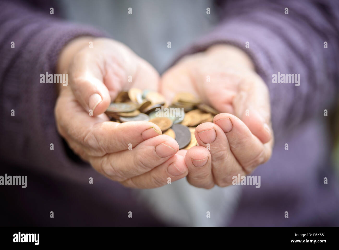 Dinero, monedas, la abuela de pensiones y el concepto de vida mínima - en las manos viejo un puñado de monedas. Cerrar Foto de stock