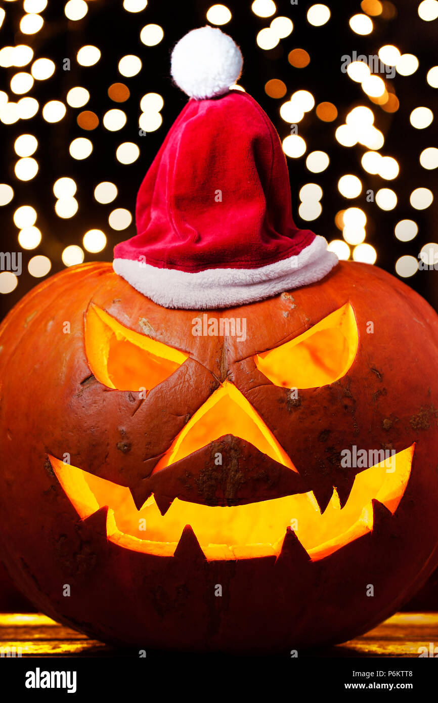Spooky halloween pumpkin Jack O Lantern brillante dentro de llevar sombrero en navidad fuera de foco de fondo luces Foto de stock
