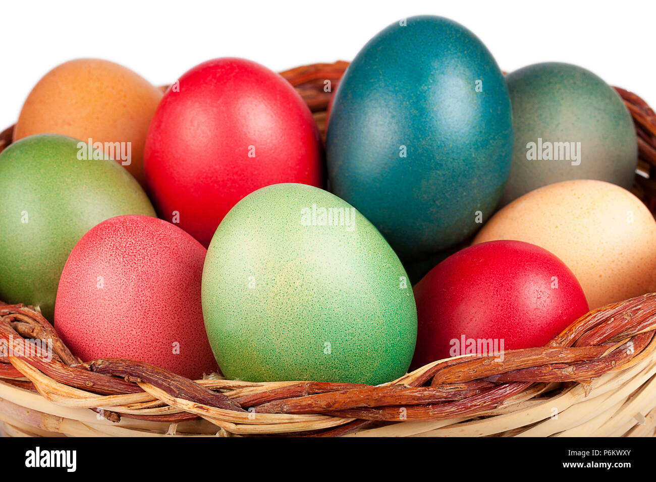 Cerca de Pascua wricked cesta llena de huevos coloreados aislado Foto de stock