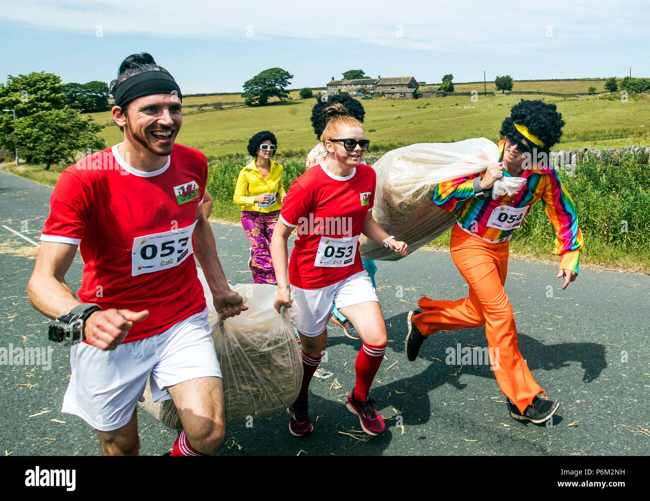Los competidores toma parte en la carrera de paja Oxenhope en Yorkshire, a 2.5 millas de carrera en Fancy Dress , llevando una paca de paja de 20 kg, mientras que la parada de las pintas de cerveza a lo largo de la ruta. Foto de stock