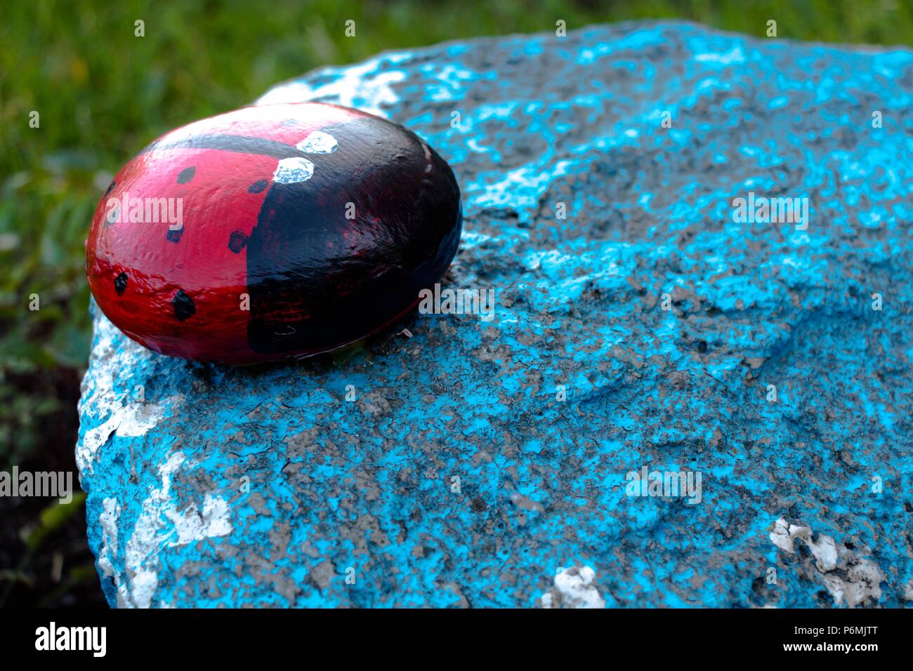 Un insecto llamado mariquita está hecha de piedra y pintado de sus tintas. La cifra se sitúa en el jardín en una piedra azul. Muy bonito e interesante h Foto de stock