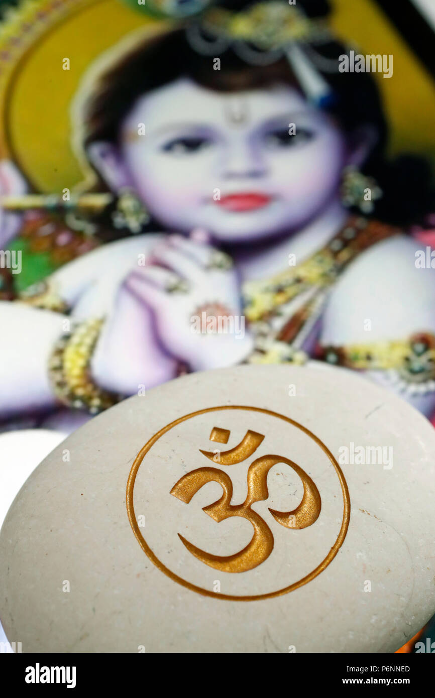 El Om o Aum símbolo del hinduismo y budismo en una piedra blanca. Imagen de bebé Krishna en un tablet. Foto de stock