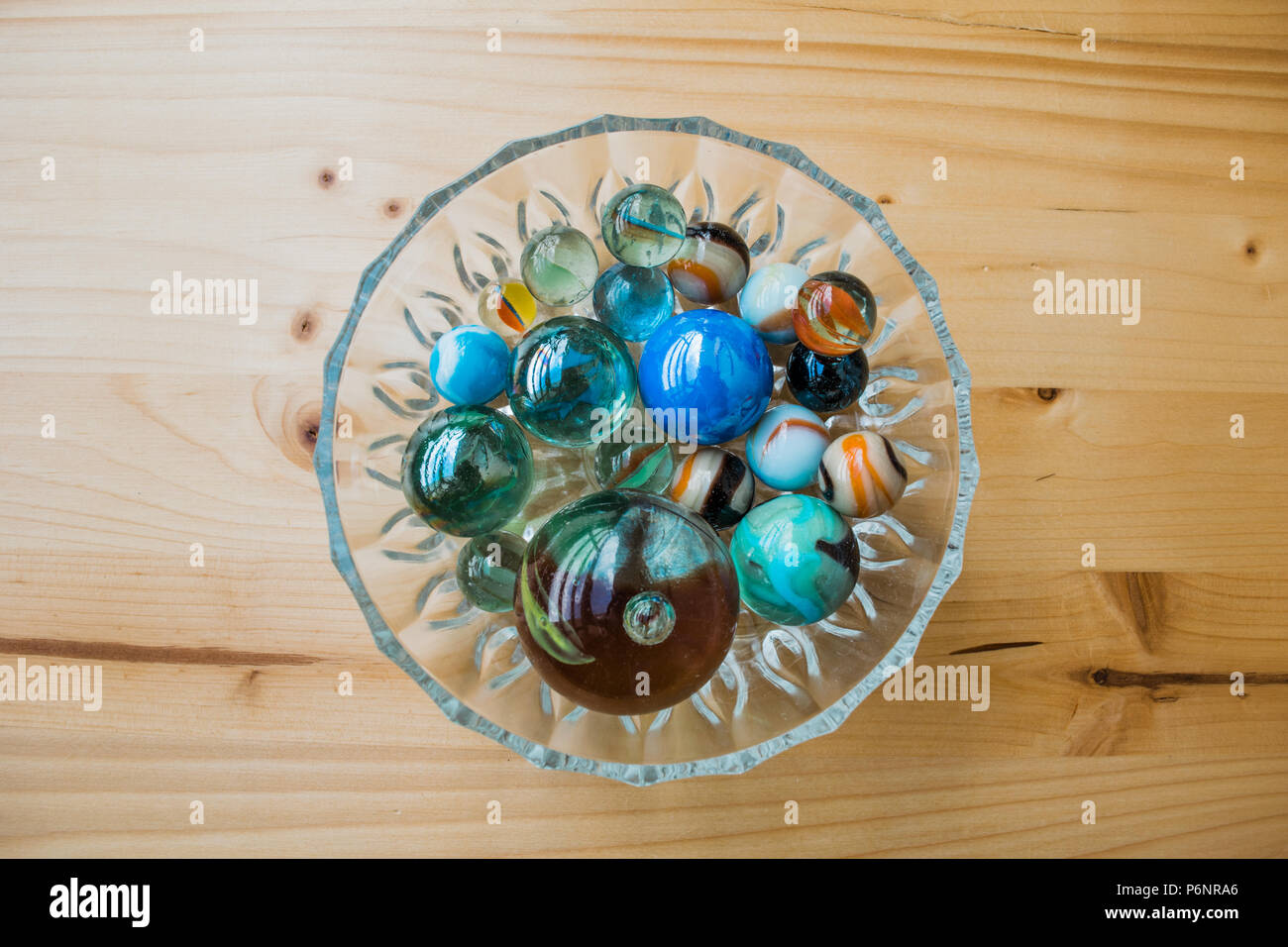 Coloridos mármoles en un recipiente sobre la mesa de madera. Foto de stock