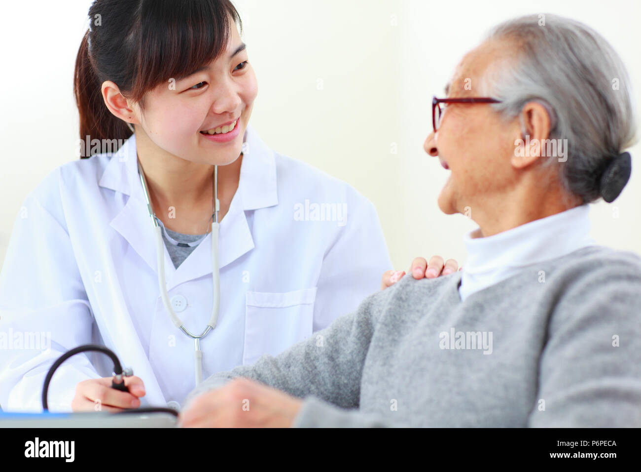 Un joven asiático doctora haciendo Health Check para altos mujer china, altos funcionarios de salud Foto de stock