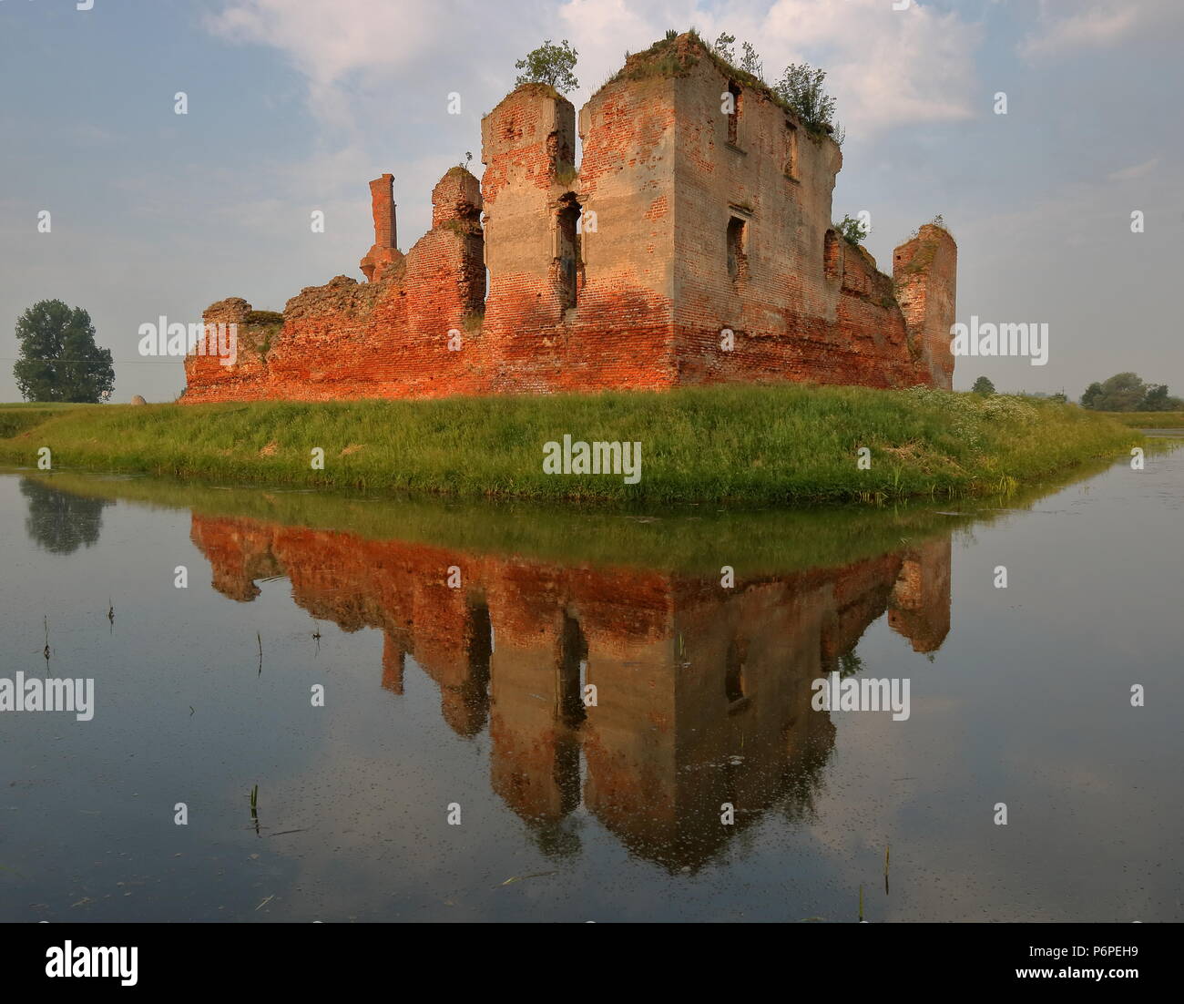 Las ruinas del castillo medieval Pictureque rodeado por agua, hermosas reflexiones sobre el agua, la luz de la mañana temprano, la larga exposición Foto de stock