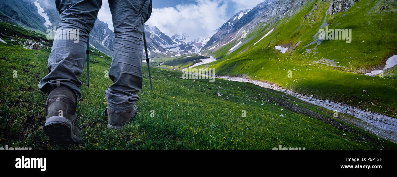 Senderismo en las montañas de nieve con botas marrones y palos y panorama. Foto de stock