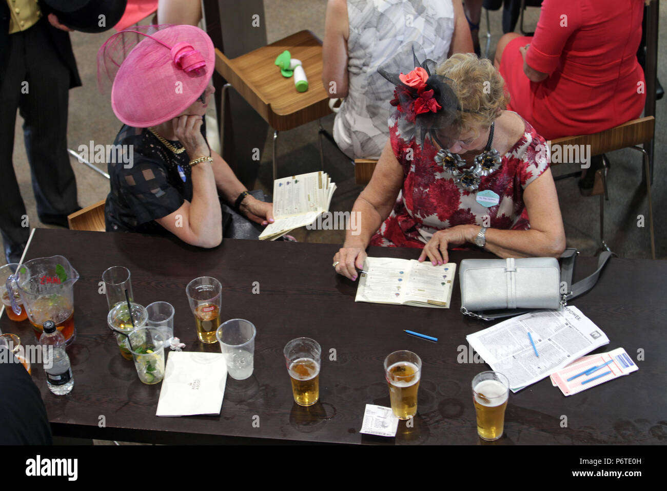 Royal Ascot, mujeres con sombreros tenga una mirada en su racecards Foto de stock
