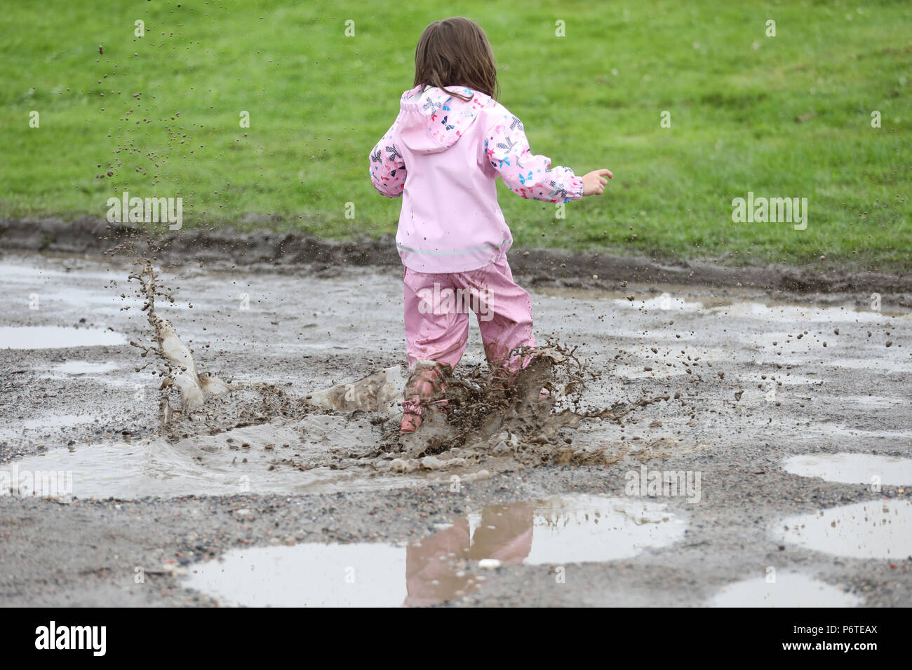 Hamburgo, niño en ropa de lluvia que se ejecutan a través de un charco Foto de stock