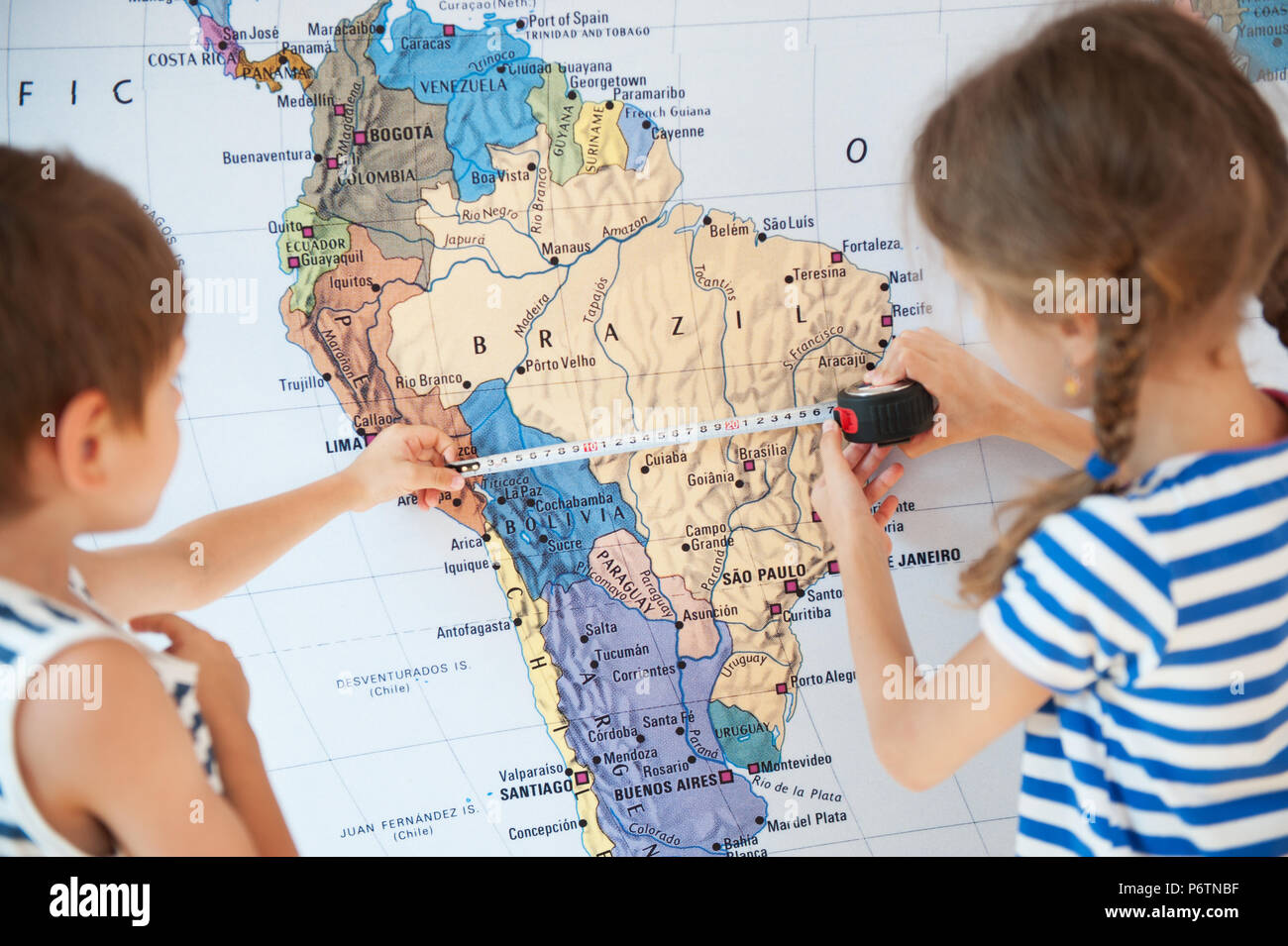 Chico y chica medir la distancia en el mapa del mundo utilizando cinta  métrica Fotografía de stock - Alamy