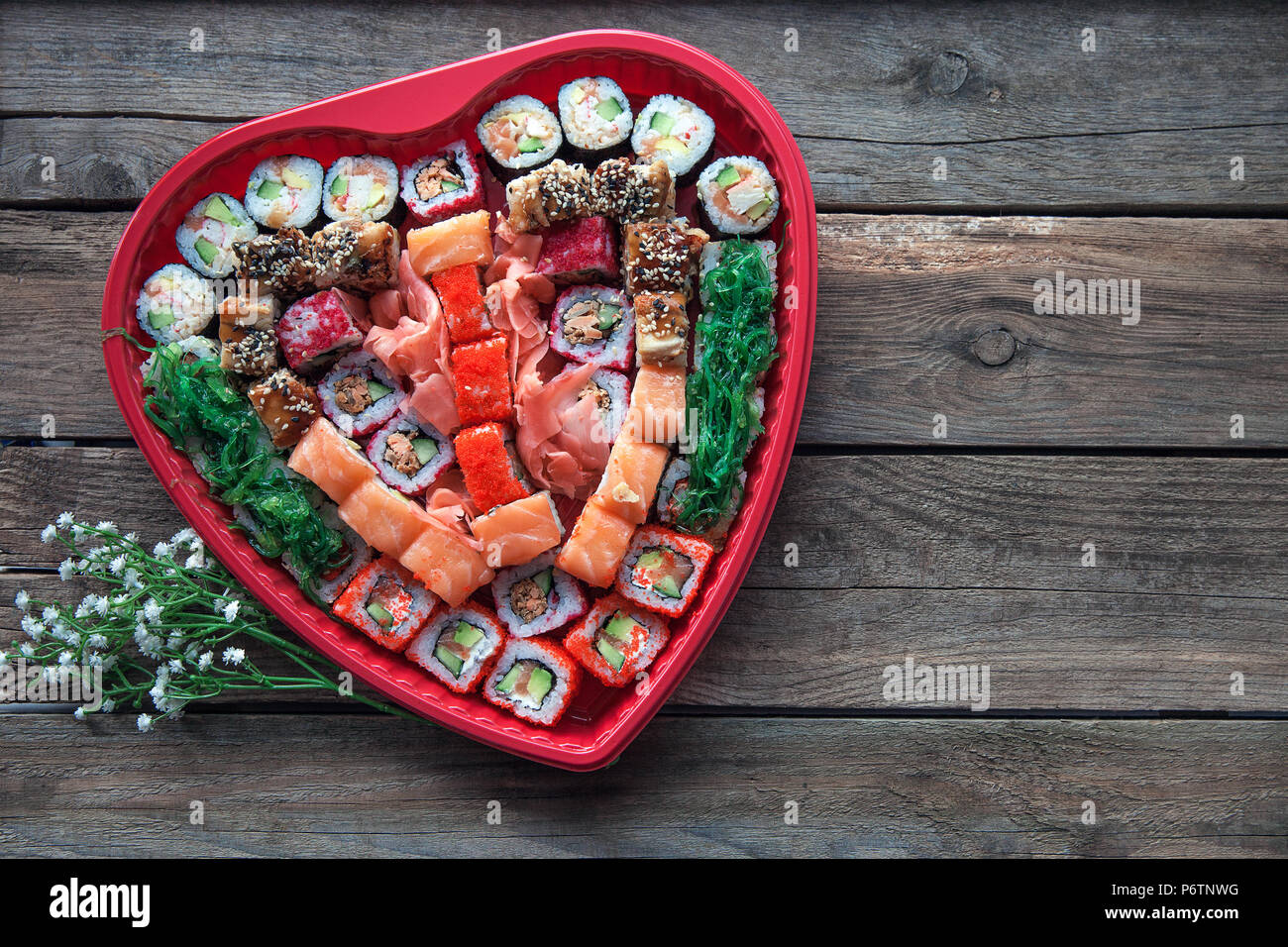 Sushi en una mesa de madera antigua del fondo con una decoración en forma de corazón Foto de stock