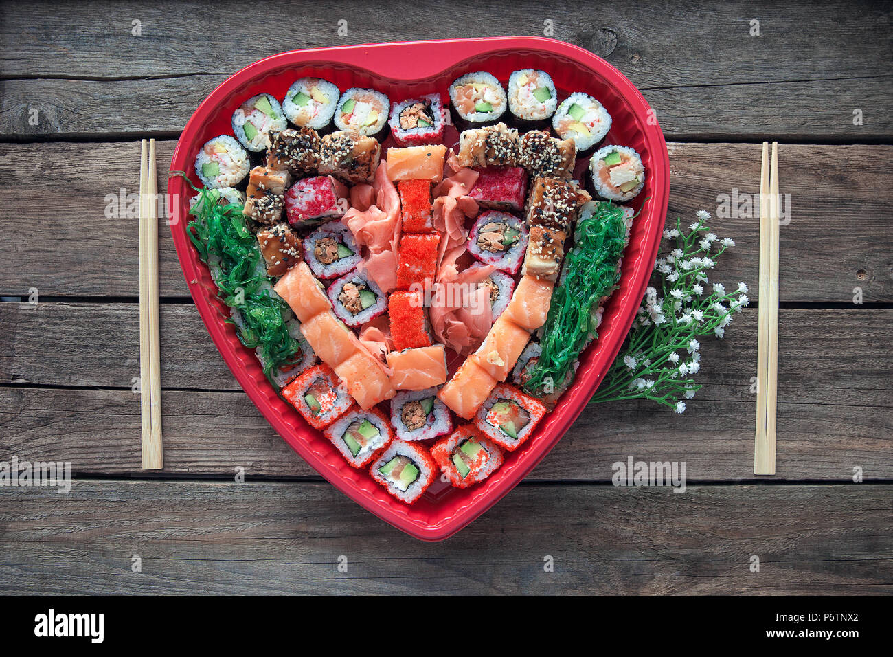 Sushi en una mesa de madera antigua del fondo con una decoración en forma de corazón Foto de stock