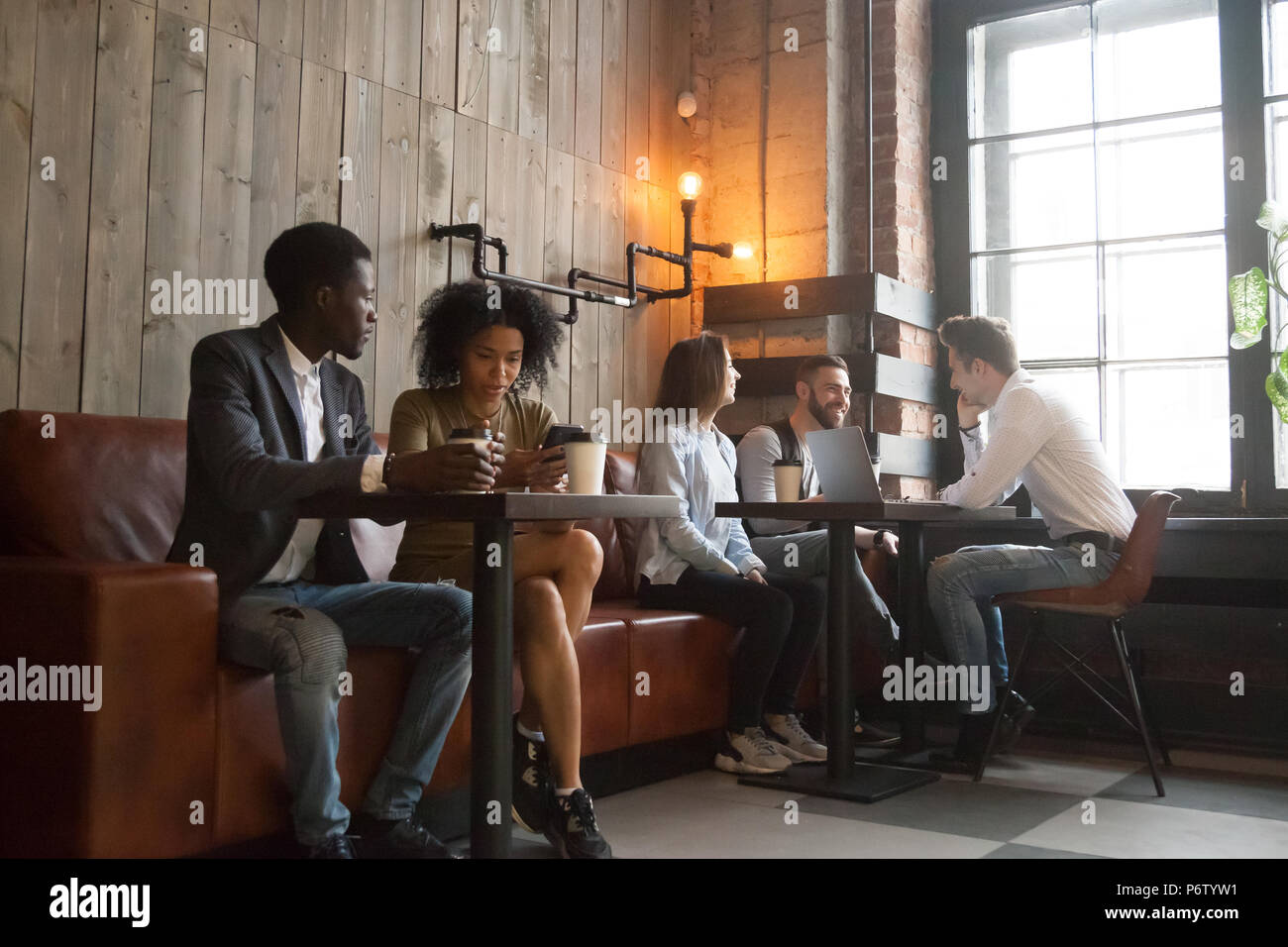 Los millennials multirracial disfrutando de café trabajando en gadgets en co Foto de stock