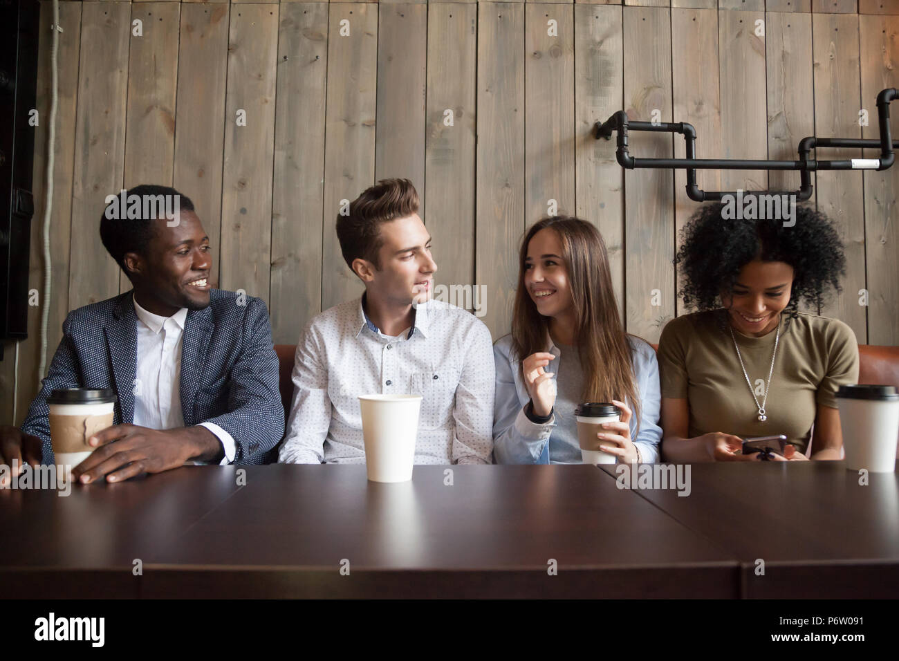 Sonrientes amigos multirraciales bebiendo café divirtiéndose en cafe Foto de stock