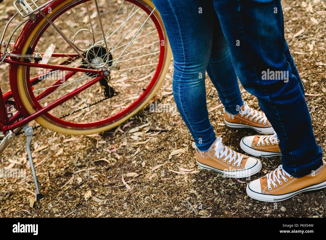 Pareja de enamorados con verde zapatillas y jeans de pie junto a una  bicicleta vintage Fotografía de stock - Alamy