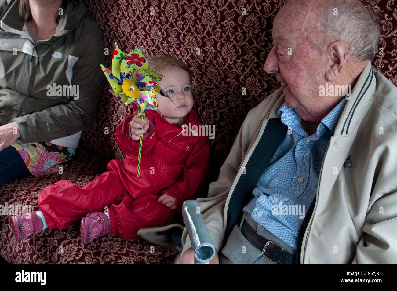 Infante mostrando su bisabuelo colorido juguete molino del niño Foto de stock