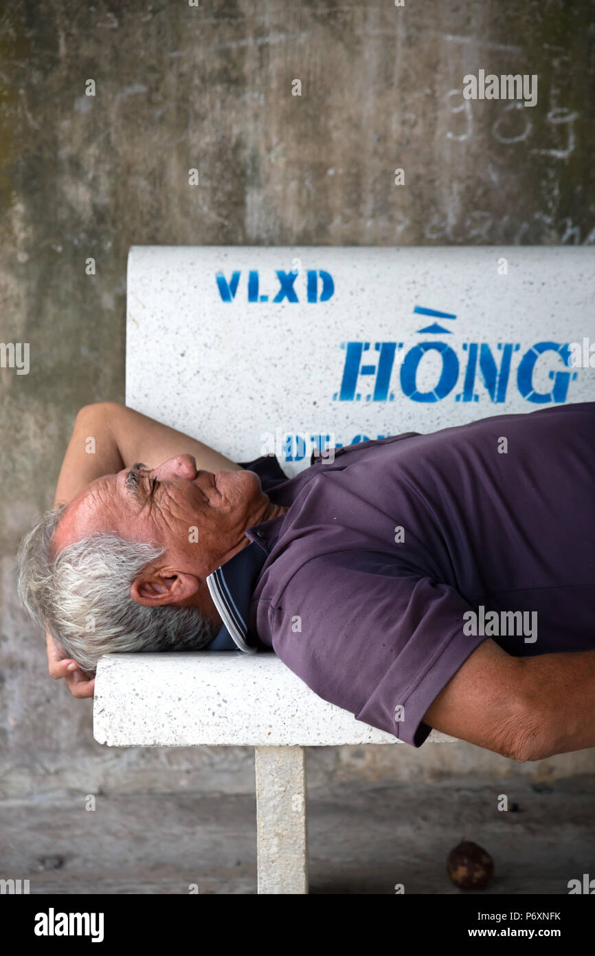 Hombre durmiendo en un banco en un Binh, Vietnam Foto de stock