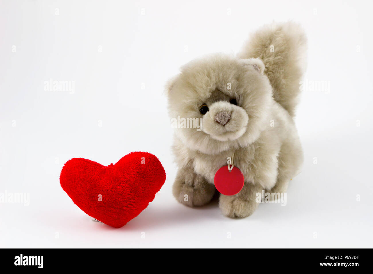 Peluche suave con corazón rojo sobre fondo blanco / Peluche Perro y corazón sobre fondo blanco / animal de juguete. Foto de stock